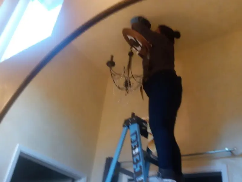 Electrician installing a chandelier in a Harvard residence